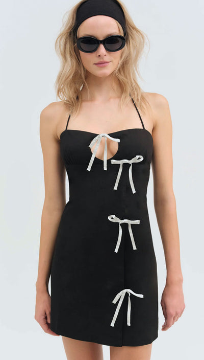 Pretty blonde Woman wearing a black dress with white bow details on a white background Helena Poplin Bow Mini Dress | For Love and Lemons